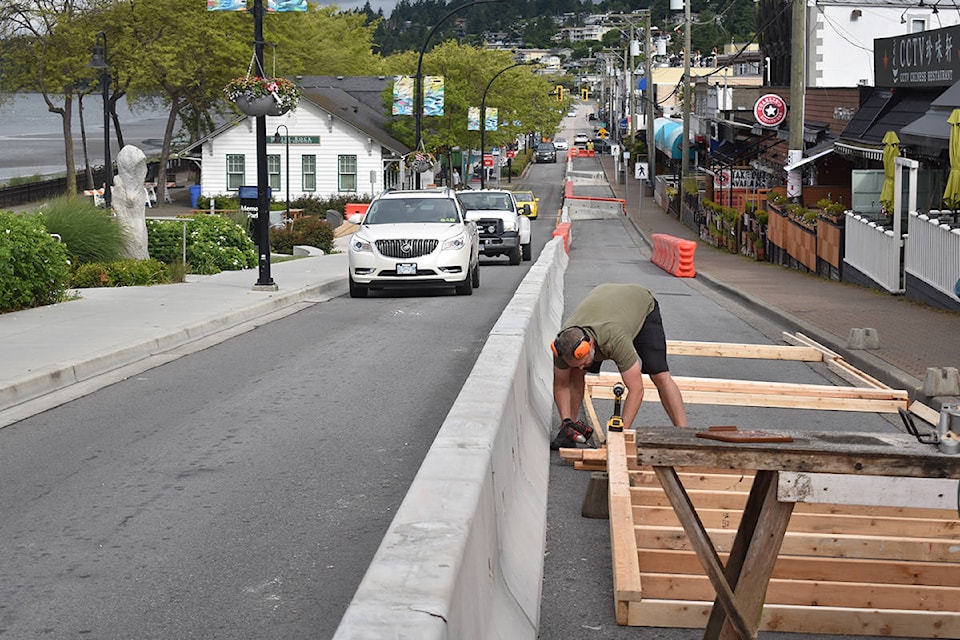 Uli’s Restaurant owner Tyson Blume builds a patio space in front of his restaurant on Marine Drive Monday morning. Sunday, city contractors placed barriers on the waterfront street and transitioned it into a one-way route. (Aaron Hinks photo)