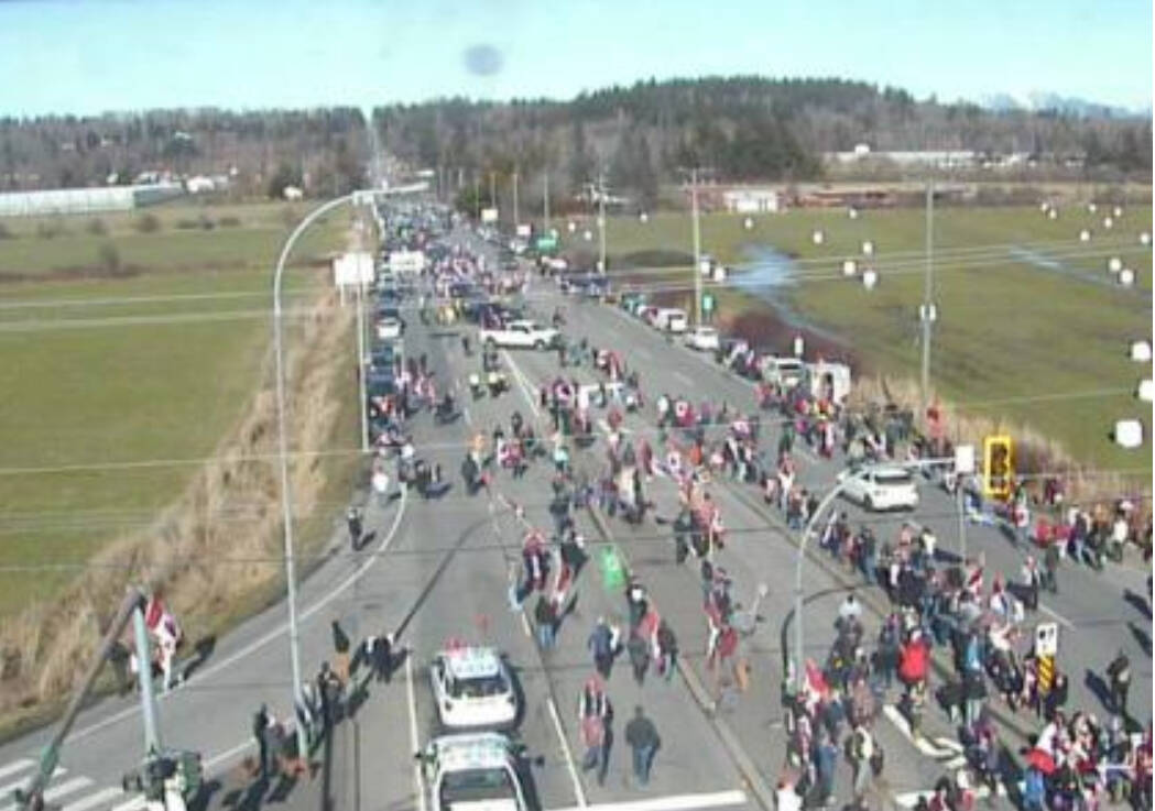 A crowd of protesters is on the road at 176 Street and 8 Avenue just before the Pacific Highway Border Crossing. (DriveBC photo)