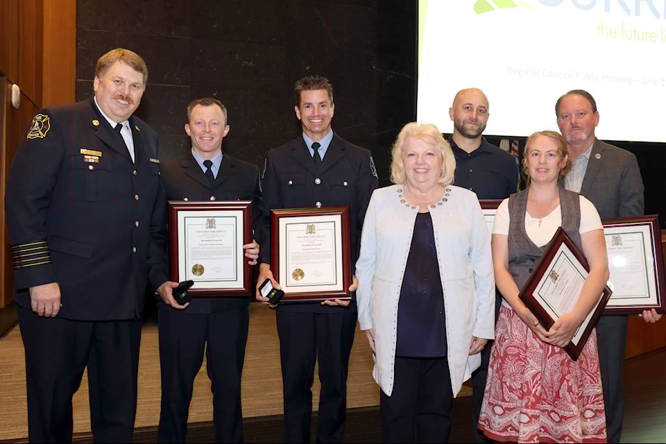 Surrey Fire Chief Larry Thomas, left, Surrey firefighters Tom McDougall and Duane Foley, Surrey Mayor Brenda Locke, Surrey RCMP Const. Steve Dalton, lifeguard Heather Jones and off-duty Burnaby firefighter Paul Rushton at City Hall Monday night, where they were honoured with Surrey Fire Service awards of merit and valour. (City of Surrey photo)