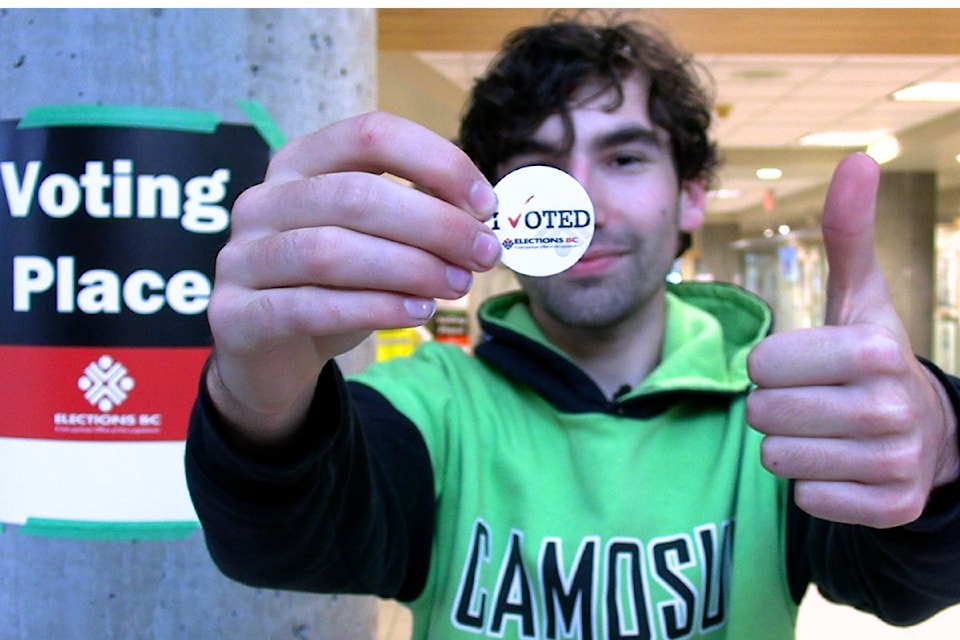 A first-time voter shows his "I Voted" sticker and a thumbs up.