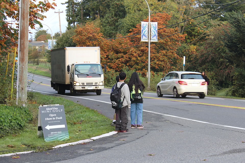 School children wait patiently for a safe moment to cross the street.