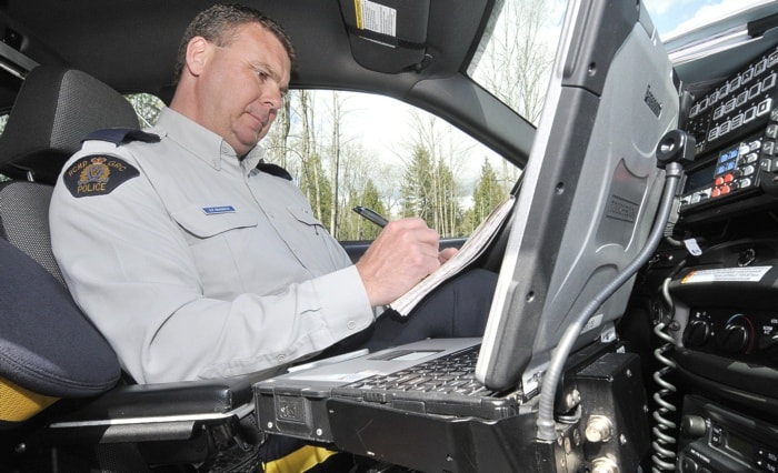 RCMP Cpl. Drew Grainger in his car working on his computer