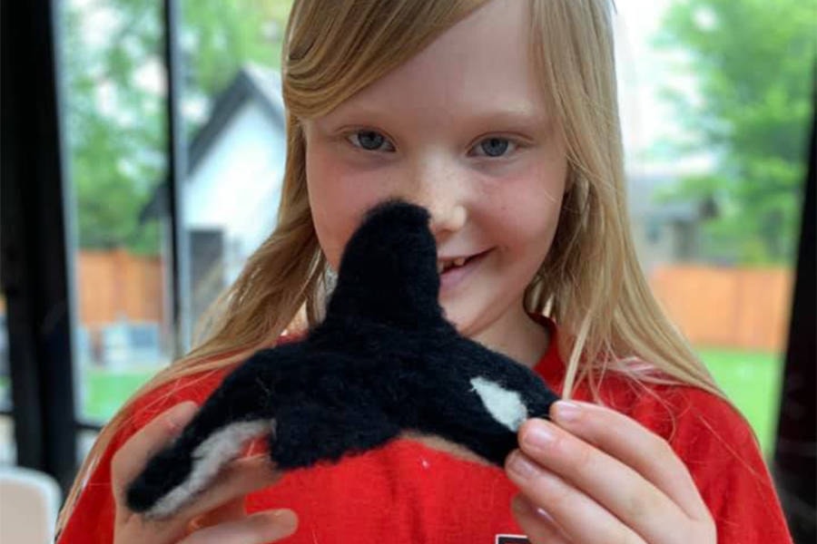 Megan Taylor’s daughter holds up a handmade needle-felted orca made from a Knotty by Nature felting kit. (Courtesy of Megan Taylor)