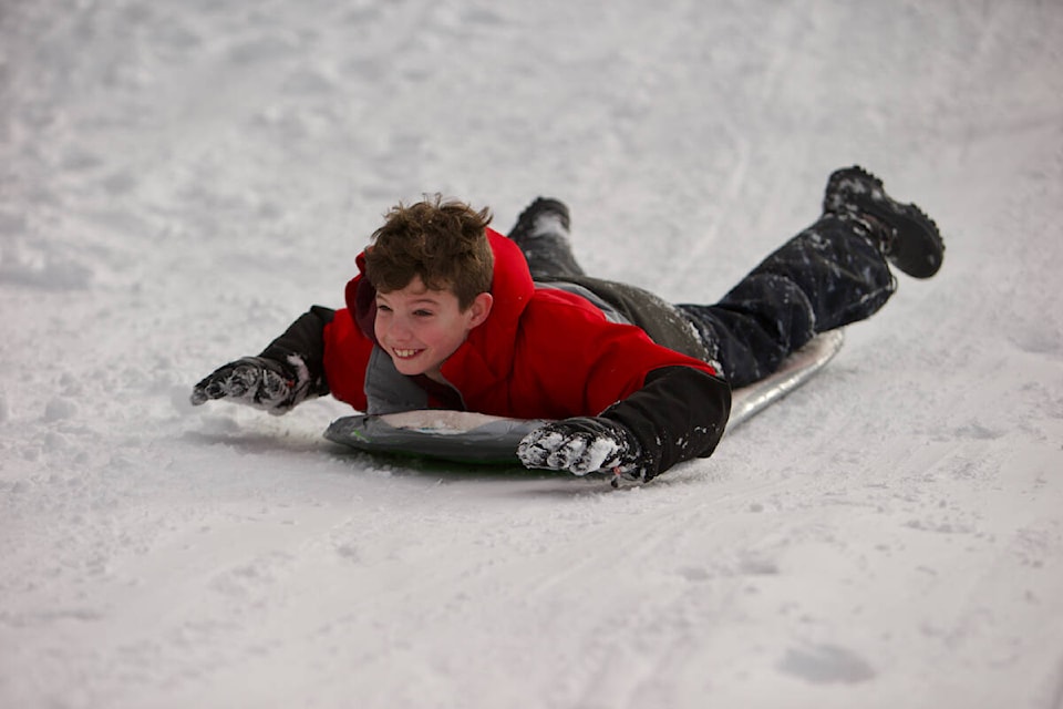 Rylan Sorrie, 9, slides down a hill near city hall Thursday. Around a dozen kids and their families were making the most of the snow. (Justin Samanski-Langille/News Staff)