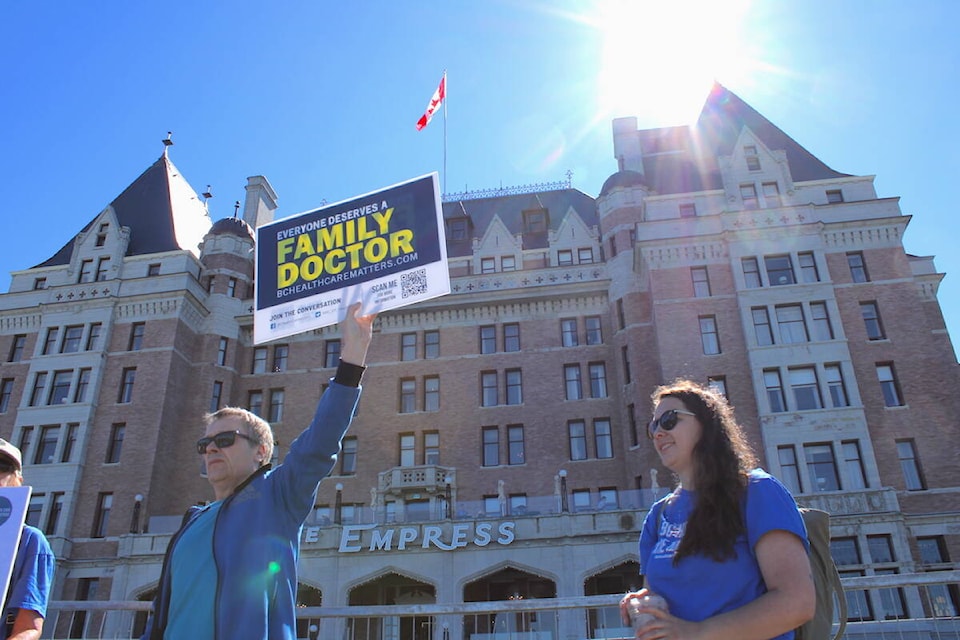 A man participating in a rally for more family doctors holds up a sign outside Victoria’s Fairmont Empress hotel, where Canada’s premiers were meeting on July 12. (Jake Romphf/News Staff)