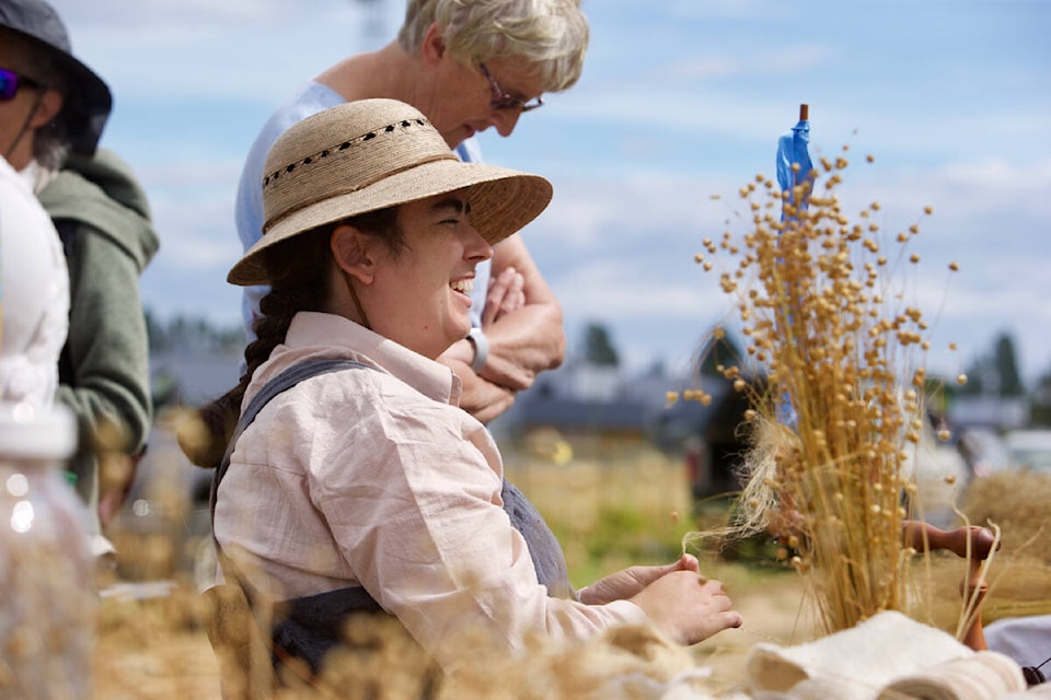 Raven Ransom speaks with visitors during a demonstration of how to turn flax seed into linen Saturday at the Sandown Regenerative Agriculture Centre as part of the 2022 North Saanich Flavour Trails event. (Justin Samanski-Langille/News Staff)