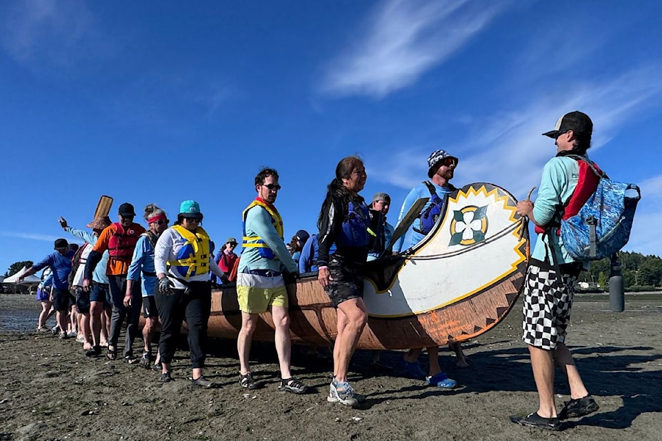Participants of the Pulling Together Canoe Journey 2025 carry their canoe to the water.