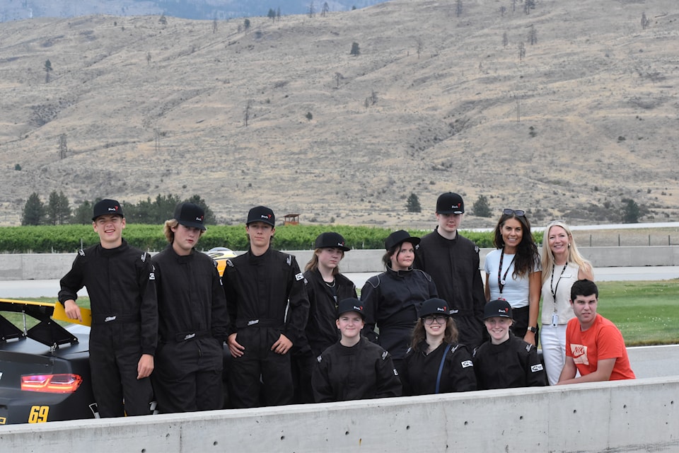 Penticton youth aged 13 to 16 from the YMCA of Southern Interior BC stand in front of a Chevrolet Camaro at Area 27 in Oliver on Aug. 28, 2025. The teens got the chance to be passenger's in the car with professional drivers. On left: Shelley Hunt, YMCA community programs manager, and Tammie Watson,  VP of Philanthropy at YMCA. 