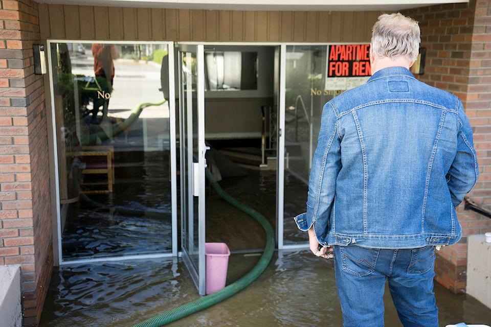 A resident of an apartment building on Rowcliffe Avenue looks over the flooded entryway of his building on May 7, 2020. (Michael Rodriguez - Kelowna Capital News)