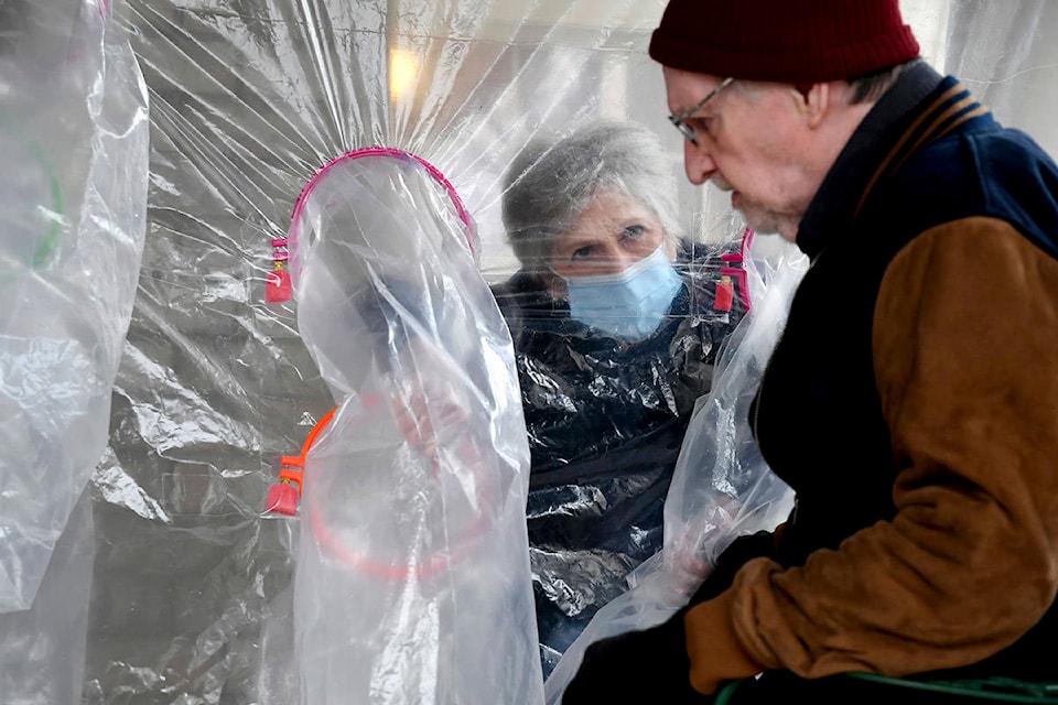 Lynda Hartman, 75, visits her 77-year-old husband, Len Hartman, in a “hug tent” set up outside the Juniper Village assisted living center in Louisville, Colo., on Wednesday, Feb. 3, 2021. (AP Photo/Thomas Peipert)