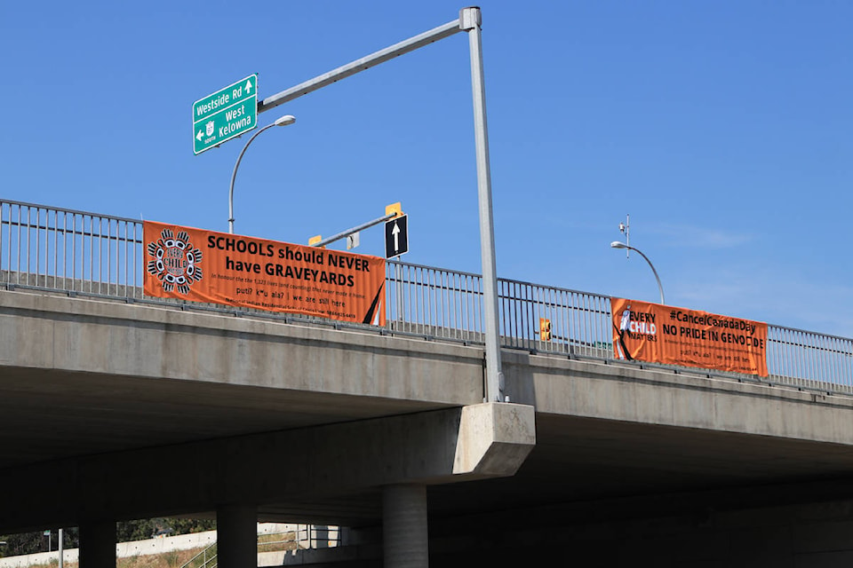 The two banners that hang over from the Westside Road interchange above Highway 97 in West Kelowna on July 1. (Aaron Hemens/Capital News)