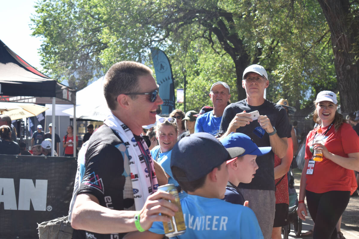 First finisher of Ironman Penticton Jeff Symonds takes pictures with fans after his win on Sunday. (Brennan Phillips Western News)