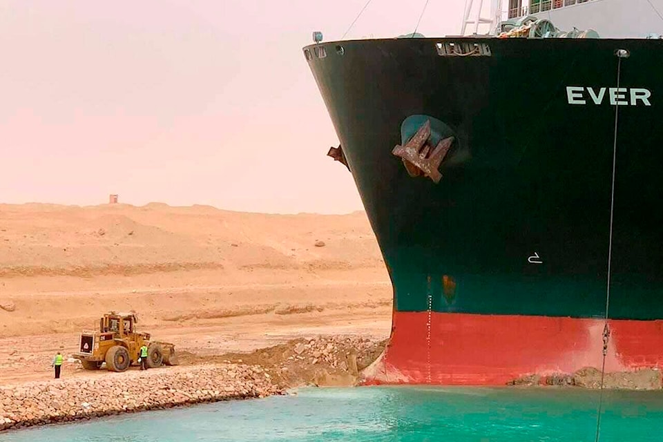 In this photo released by the Suez Canal Authority, a cargo ship, named the MV Ever Given, sits with its bow stuck into the wall Wednesday, March 24, 2021, after it turned sideways in Egypt’s Suez Canal, blocking traffic in a crucial East-West waterway for global shipping. An Egyptian official warned Wednesday it could take at least two days to clear the ship. (Suez Canal Authority via AP)