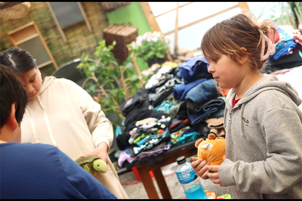 Children look through donated items at the Riverbank Common on May 7, after a fire on May 6 burned down six town house units in Ponoka.