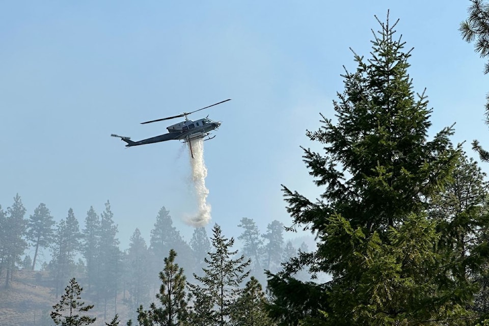 A helicopter drops water on a wildfire south of Campbell Mountain near Sendero Canyon on Aug. 25, 2025.