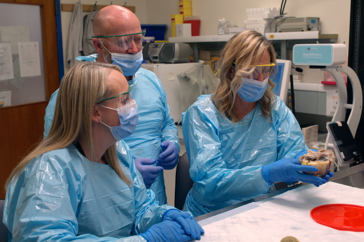 Angela Neufeld holds her original heart while her husband and sister look on