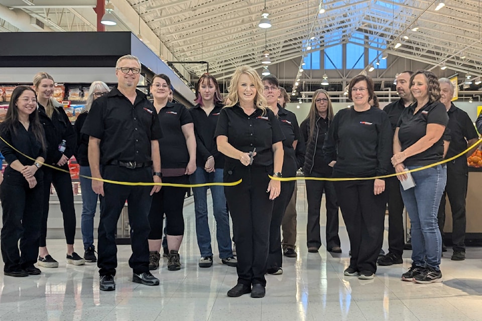 Tobi Weightman cuts the ribbon in front of the No Frills staff, signalling the official opening of the grocery store which was rebranded from Extra Foods.