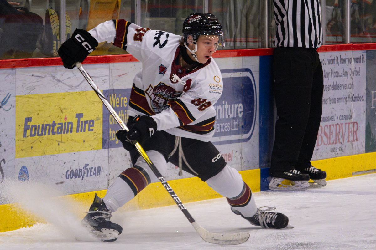 Cash Anderson turns quickly on his skates, spraying ice and controlling the puck