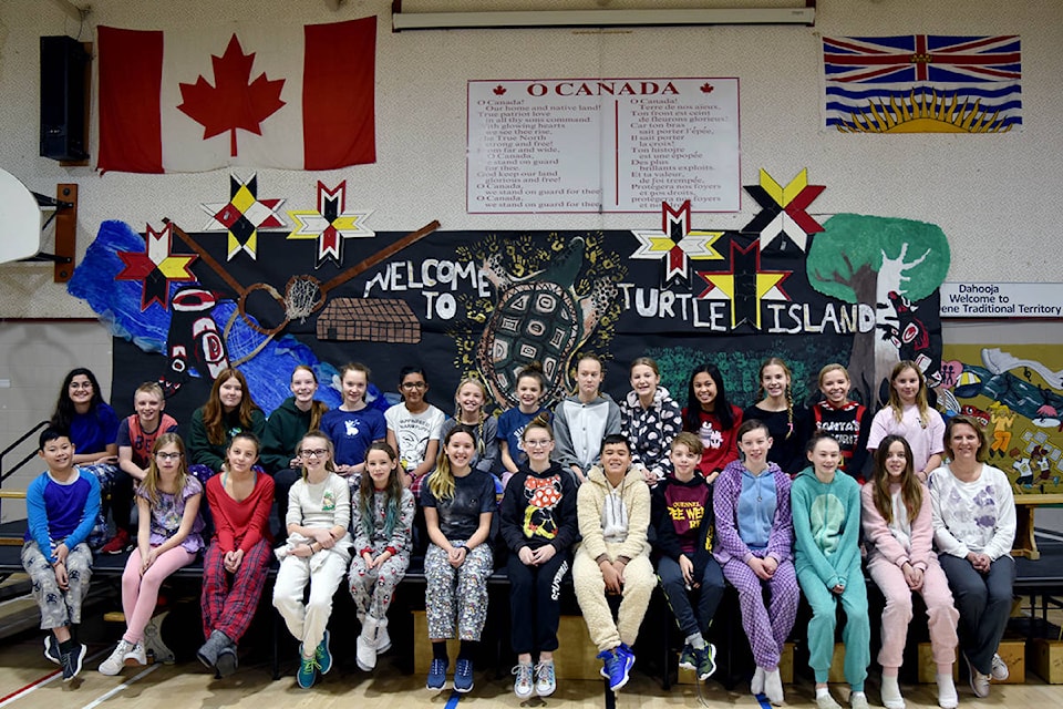 Laura Volk’s grade 6/7 French immersion class smiles for a photo in front of their mural on the school’s pajama day. The mural will form the backdrop of their Christmas concert at Red Bluff Lhtako Elementary School. Heather Norman photos