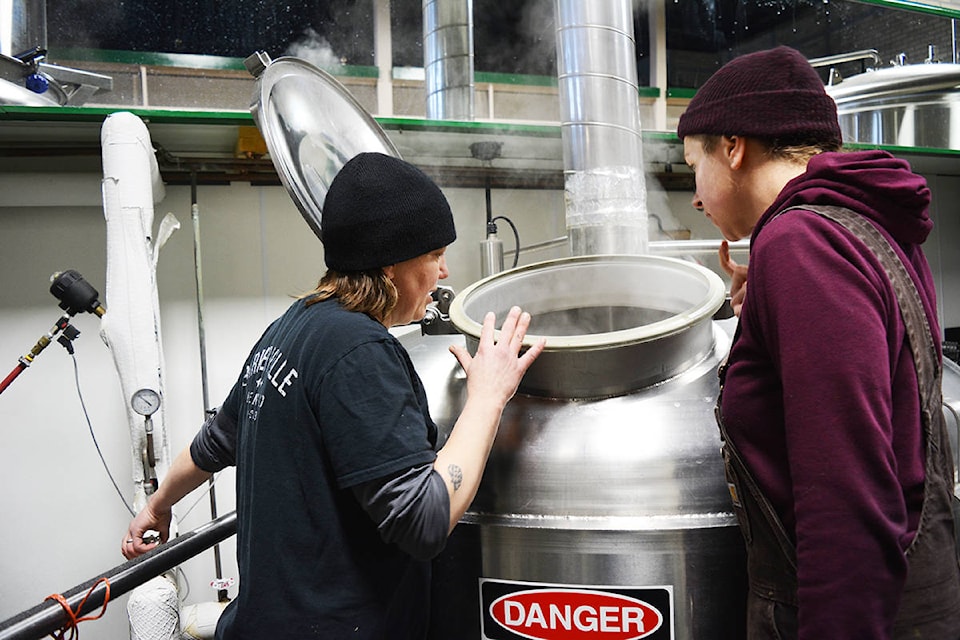 Above, Erin Dale and Janelle Harder check the brew kettle/whirlpool to see if it is boiling, while below, Josh Skarbo from the South Quesnel Liquor Store adds hops to the brew kettle/whirlpool. Lindsay Chung photos