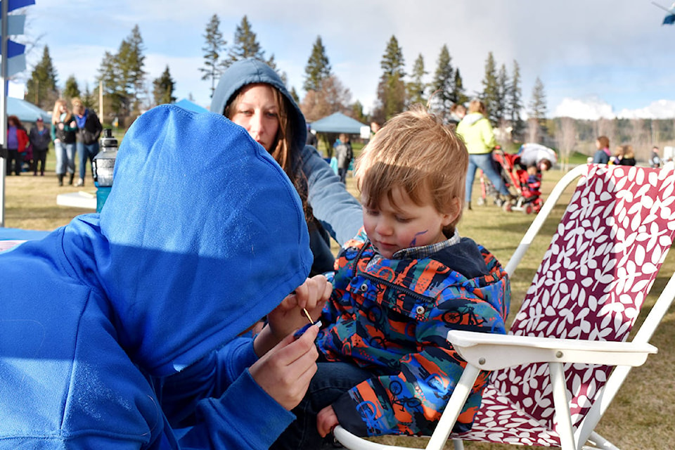 A child has his face painted by Shaina McCrae at the rally and party for autism awareness at LeBourdais Park on Sunday, April 14.