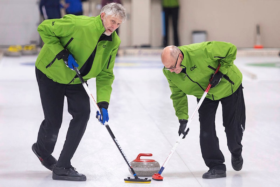 Ben Ruether (left) and Dean Rubisch of the Quesnel and District Child Development Centre curling team sweep hard during a Quesnel Sponsor League match at the Quesnel Curling Centre on Dec. 11. (Sasha Sefter - Quesnel Cariboo Observer)