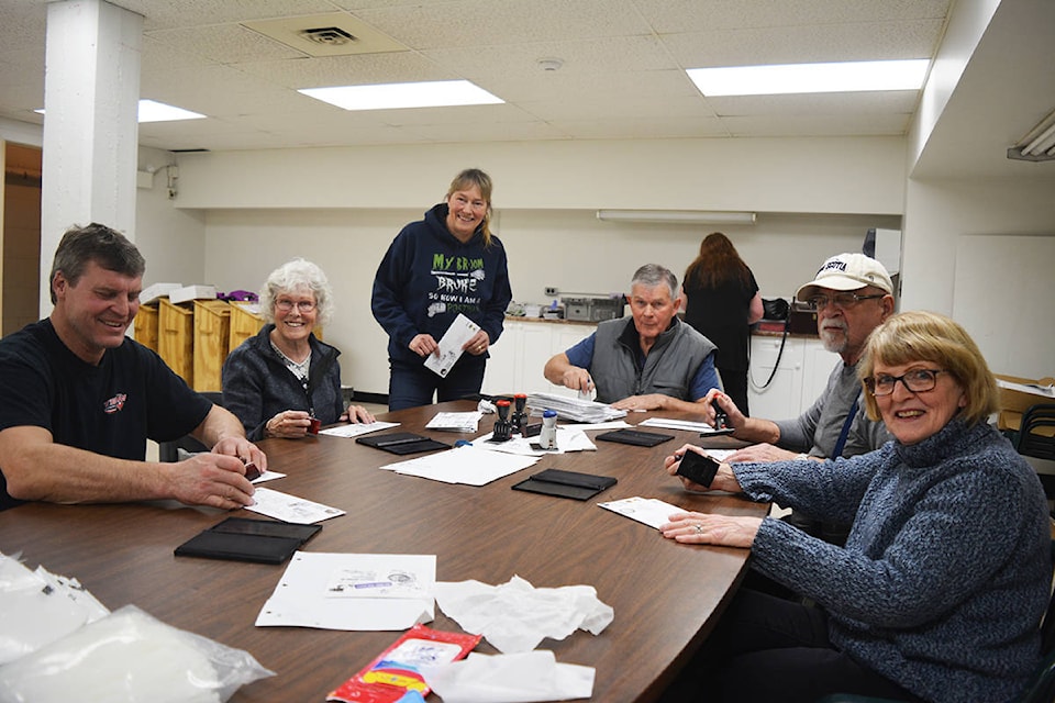 Volunteers stamp envelopes for the Gold Rush Trail Sled Dog Mail Run Thursday, Jan. 23. Because there are post offices operating in Quesnel, Wells and Barkerville on the route, the envelopes must all be hand-cancelled for those post offices, and the envelopes are also stamped “Carried by dogsled.” (Lindsay Chung - Quesnel Cariboo Observer)