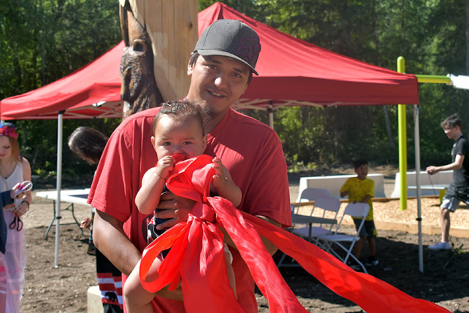 Connelly Longe holds daughter Alayna after helping cut the ribbon to George Longe Memorial Park on Wednesday, August 5. (Rebecca Dyok photo)
