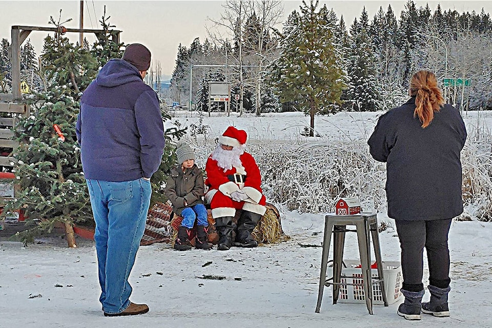 Santa (Michael Raftery) chats with a youngster outside the Bouchie Lake Country Store on Sunday, Dec. 5. (Rebecca Dyok photo)