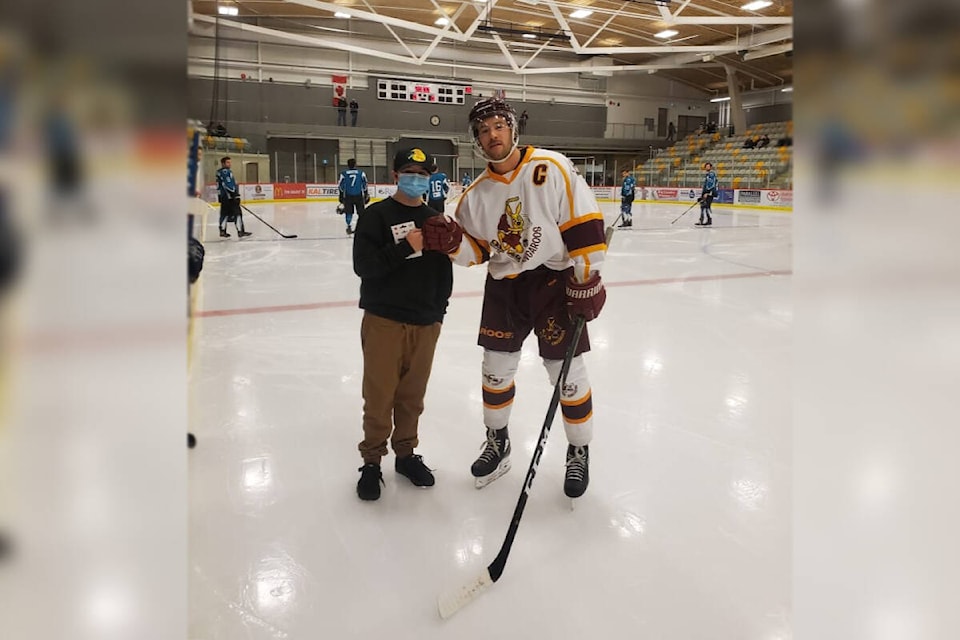 Landdyn Diplock is presented with a gift card for new hockey equipment by Quesnel Kangaroos captain Alessio Tomassetti Saturday, Jan. 8. The 11-year-old had lost his hockey equipment in a recent house fire. (Photo submitted)