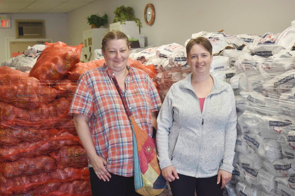 Cindy Mighton and Coral Byrd with the Quesnel GreenHope Society stand by some of the potatoes up for grabs inside the Quesnel Community Living Association. (Rebecca Dyok photo — Quesnel Observer)