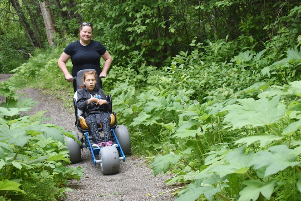 Jenny Brautigam takes her daughter Brooke down a trail at West Fraser Timber Park in a new all-terrain wheelchair on Thursday, June 16. (Rebecca Dyok photo — Quesnel Observer)