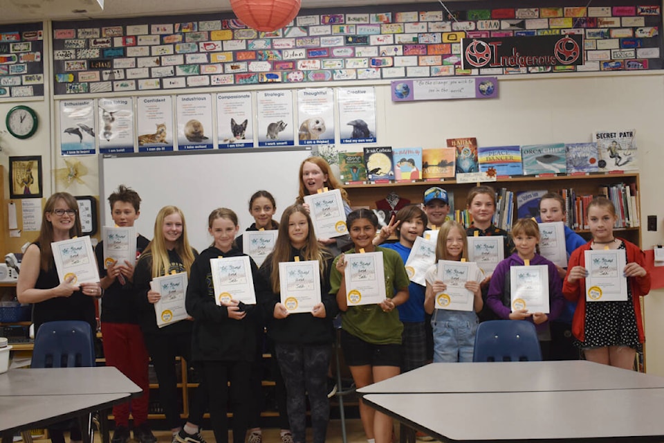 École Red Bluff Lhtako students hold copies of their written and illustrated book Of Sand and Sea on Friday, June 17, with teacher librarian Teresa Mccart. (Rebecca Dyok photo — Quesnel Observer)