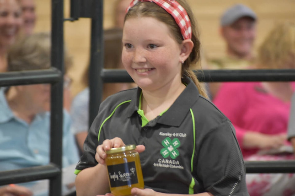 Bria Sanford holds up a jar of honey at the Quesnel and District 4-H Show and Sale. The three jars sold for $290. (Rebecca Dyok photo — Quesnel Observer)