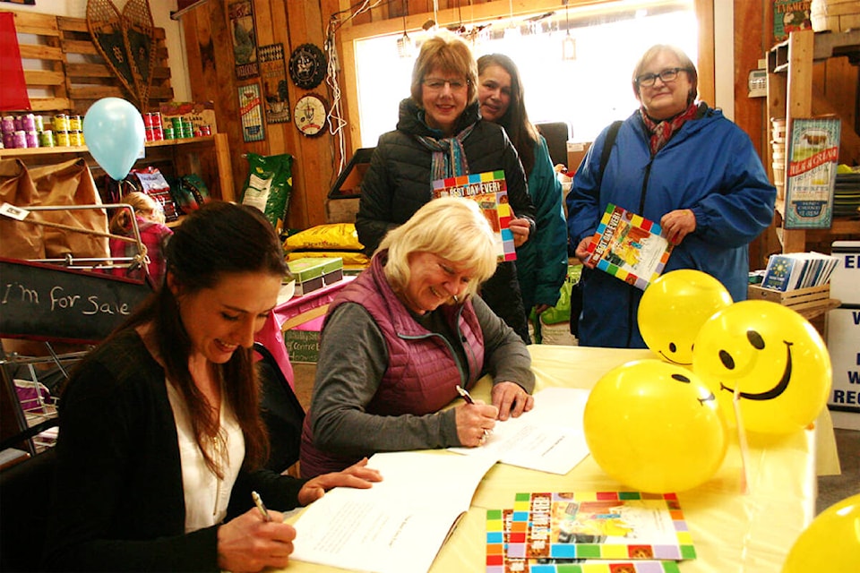 Quesnel children’s author Kathy Fowkes (right at table) sits with illustrator Tiffany Jorgensen to sign one of the many books on which they have collaborated. (Black Press file photo)