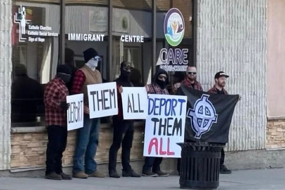 A group of men was pictured carrying signs saying 'deport them all' in Red Deer this past weekend. (Photo via Red Deer Vibin/Instagram)