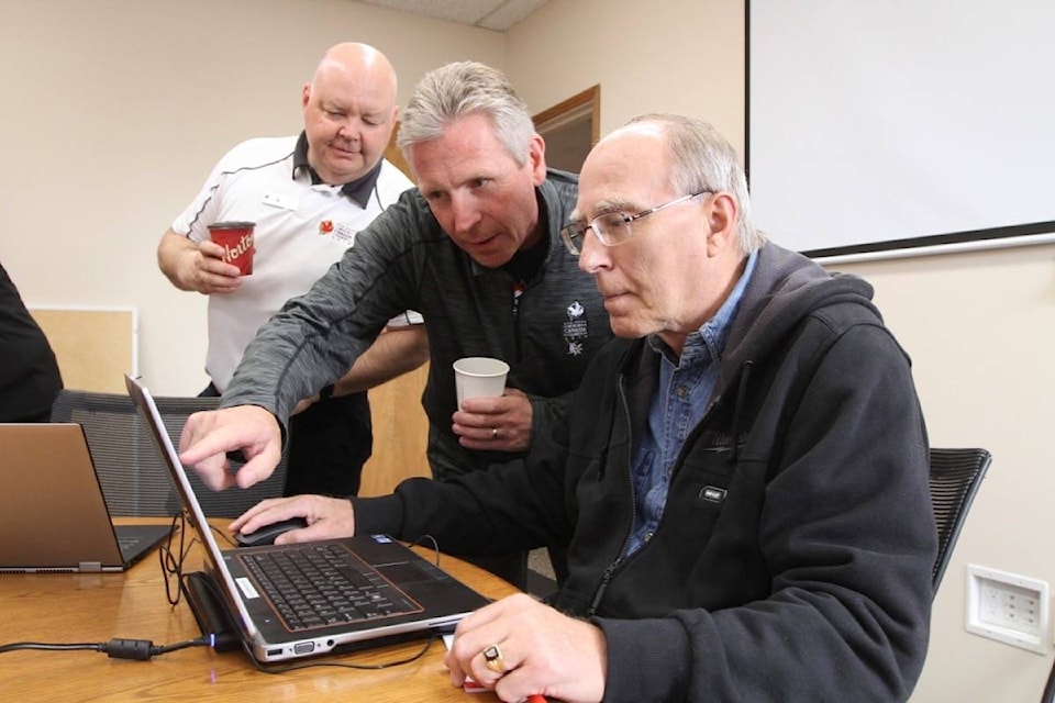 Mark Baron, with 2019 Canada Winter Games volunteer services, helps Red Deer’s Wayne Clark (right) sign up to be a volunteer as Scott Robinson, games CEO, looks on during a volunteer centre open house Saturday at the Ing and McKee Insurance office on Bremner Avenue. (Photo by SEAN MCINTOSH/Advocate staff)