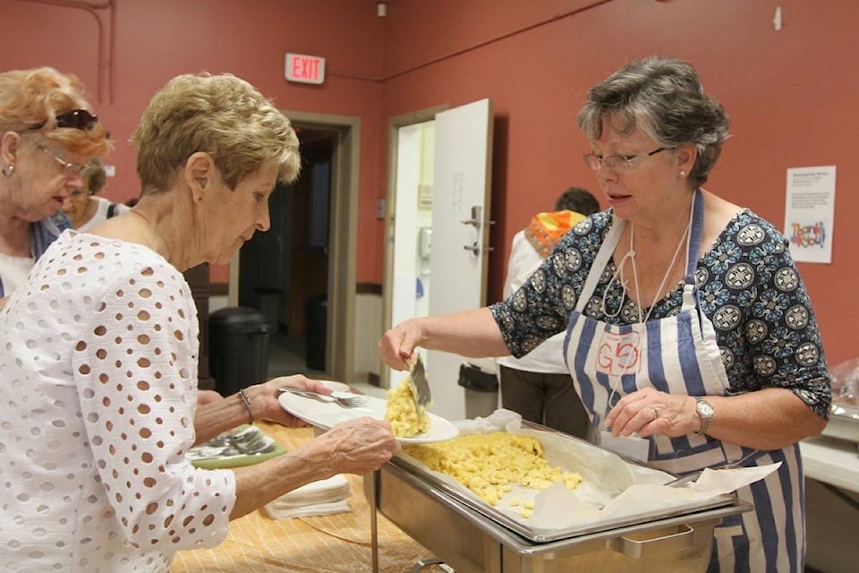 Bonnie-Jean Brown fills Heather Hamill’s plate at the GrammaLink-Africa Mac and Cheese for a Cause Luncheon Wednesday at the Gaetz United Church in Red Deer. All proceeds from the event go to the Stephen Lewis Foundation to support African Grandmothers raising grandchildren orphaned by HIV/AIDS. (Photo by SEAN MCINTOSH/Advocate staff)