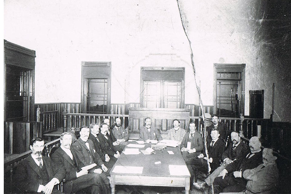 Revelstoke Board of Trade in original local courthouse, circa 1897. From bottom left: Dr. W.B. McKechnie, B.R. Atkins, T.E.L. Taylor, unknown, unknown, F.B. Wells, T. Haig, Mr. Hearne, Charles Shaw, Mr. Brewster, Robert Tapping, unknown (in back), Robert Wilson, unknown, H.A. Brown, unknown. (Photo from Revelstoke Museum and Archives)