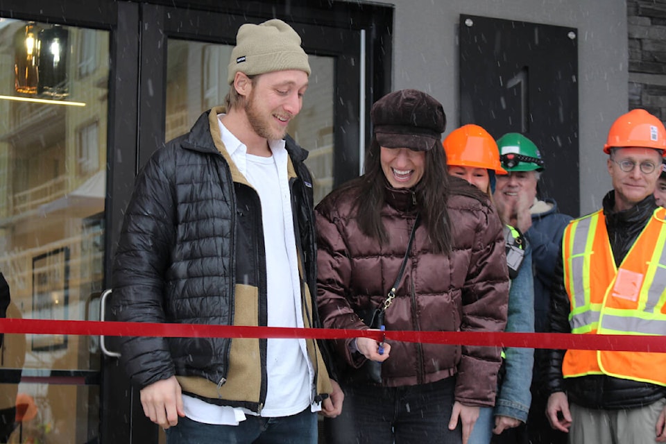 Cameron McGeough and Rio Hanlan cutting the ribbon at Mackenzie Plaza in front of a crowd of workers, developers, and members of city council ahead of moving into their new condo next week. (Josh Piercey/Revelstoke Review)
