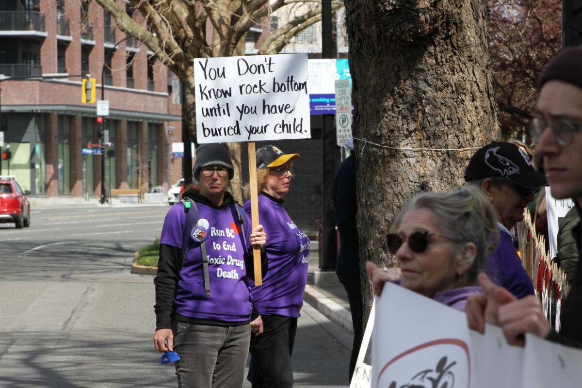 Jessica Michalofsky holds a sign facing out towards traffic at a safe supply rally outside the B.C. Ministry of Health in downtown Victoria April 14. (Austin Westphal/News Staff)