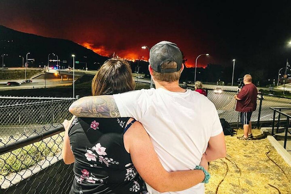 A couple watching their neighbourhood burn after being evacuated from West Kelowna on Aug. 17. (Jacqueline Gelineau/Capital News)