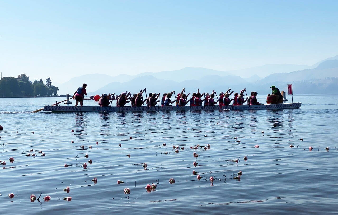 After the carnation ceremony, the Robuster/Spirit Abreast team paddles through floating carnations with coach Joy Andersen in the front seat, up the boat without a paddle because of a shoulder injury. Photo: Otter Louis