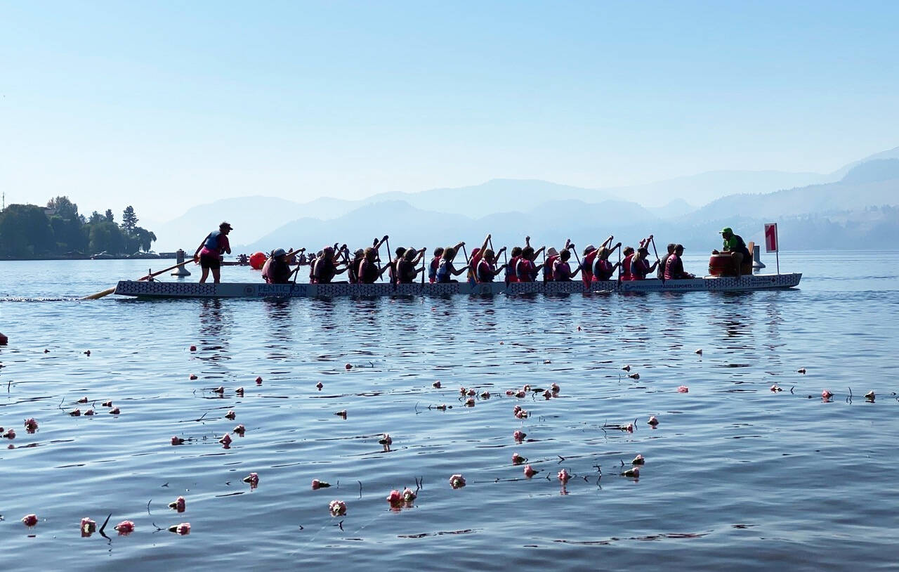 After the carnation ceremony, the Robuster/Spirit Abreast team paddles through floating carnations with coach Joy Andersen in the front seat, up the boat without a paddle because of a shoulder injury. Photo: Otter Louis