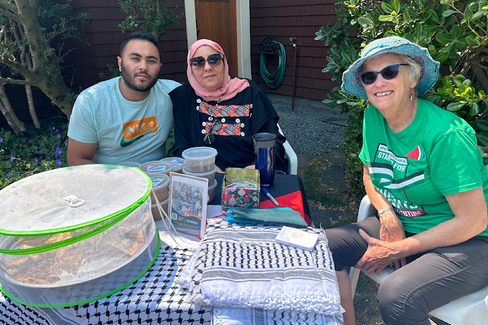 Amal Alhaddad, center, sits with her son Mousa Alhaddad and Barbara Hansen at the garage sale benefit raising money to get the Alhaddad's family out of Gaza.
