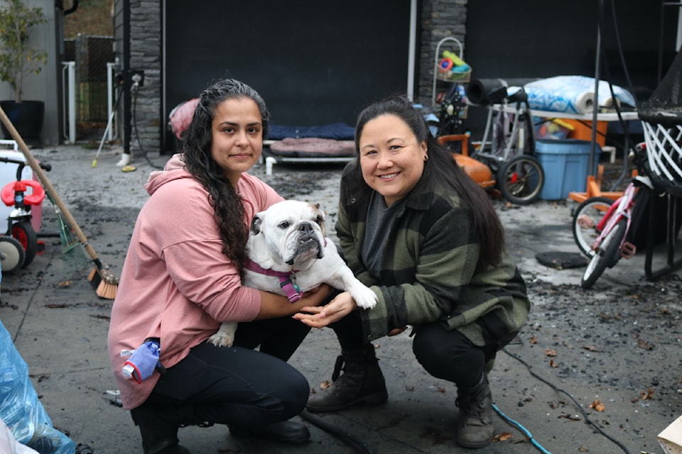 Victoria Bulldog Society's Melanie Dry and volunteer Katy Mukai, with Gerty, surrounded by fire damage caused by the Nov. 20 blaze on Quadra Street.