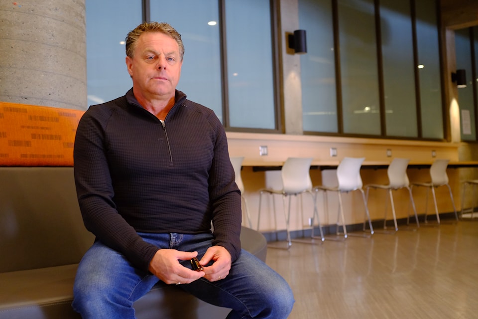 Wayne Kelly sits inside the McKinnon building, in front of windows that once overlooked the pool. Since September 2024, the glass has been painted over, blocking any view of the now-empty facility.