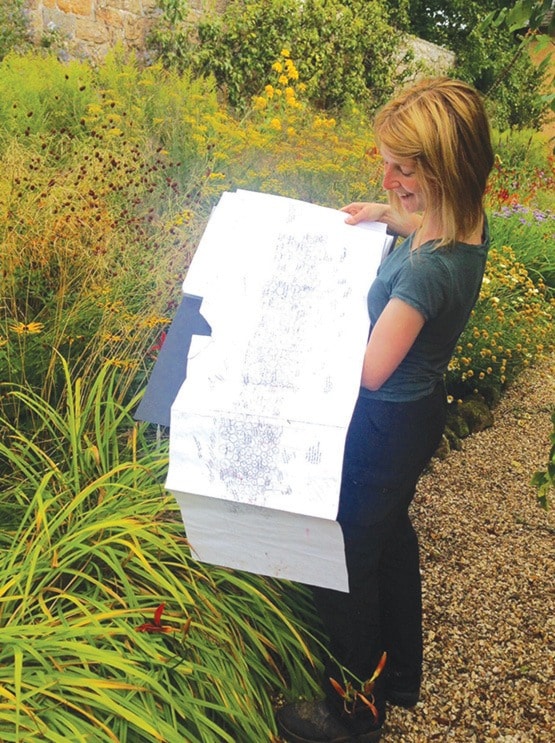 Fiona Coull holds a hand-drawn guide to a herbaceous border.