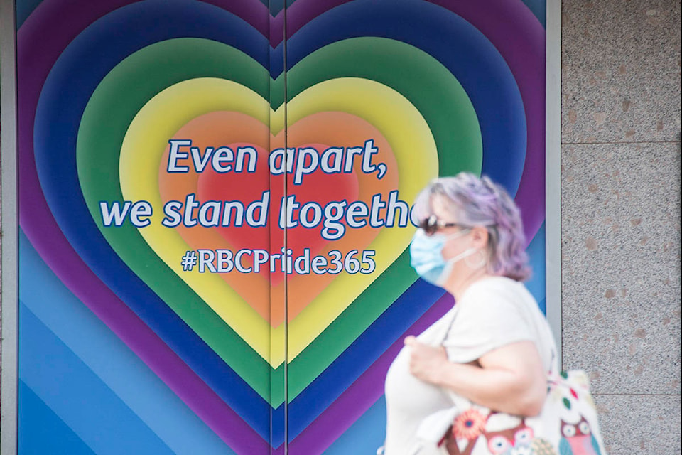 A woman walks past a sign celebrating pride on the corner of Fort and Douglas streets. Victoria Pride celebrations went virtual this year in response to the COVID-19 pandemic. (Nina Grossman/News Staff)