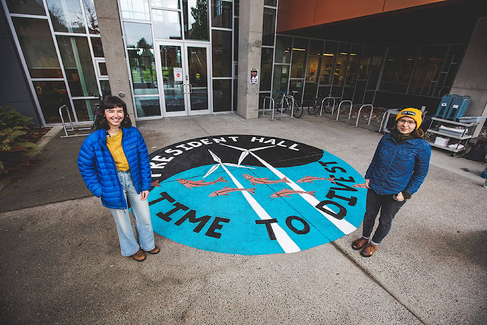 Emily Lowan and Emily Thiessen stand by the completed mural. (Photo by Colin Smith)